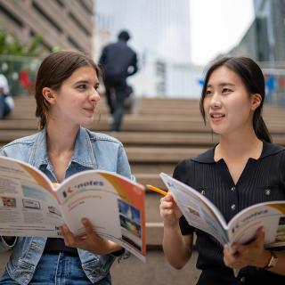 two students looking at brochure on stairs