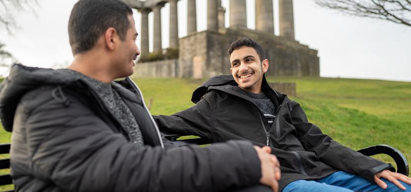 two students talking together on a bench