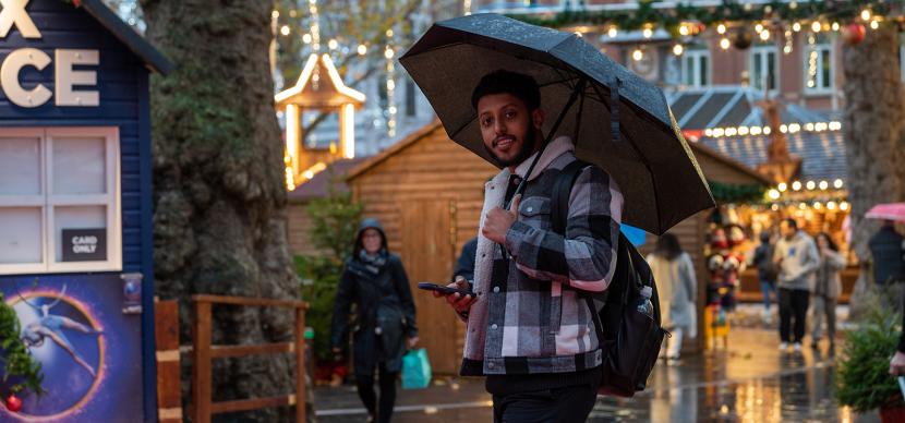 student with an umbrella under the rain in london
