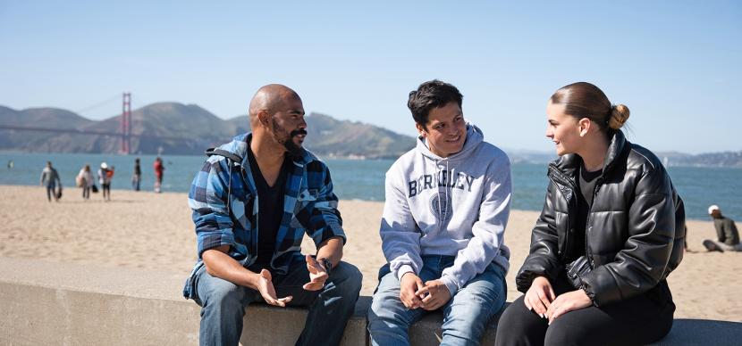 3 students talking together on the beach