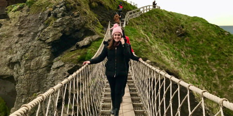 Girl on bridge, green hills surround her