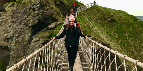 Girl on bridge, green hills surround her 