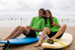 two girls sitting on their surfboards on a beach