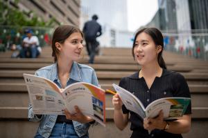 two students looking at brochure on stairs