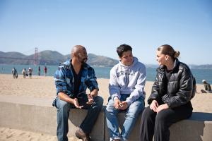 3 students talking together on the beach