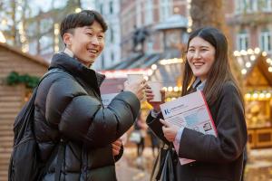 two students having a drink in the christmas market