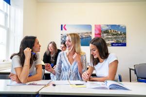 3 students talking together in a classroom