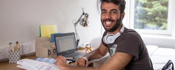 student working on his laptop in his room