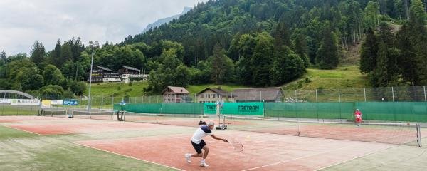 student playing tennis with teacher