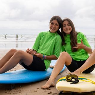 two girls sitting on their surfboards on a beach