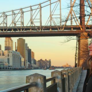 girl looking at the river with a bridge behind