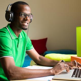 student working on his laptop in his room