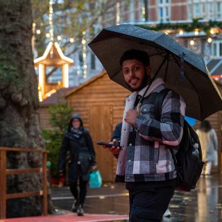 student with an umbrella under the rain in london